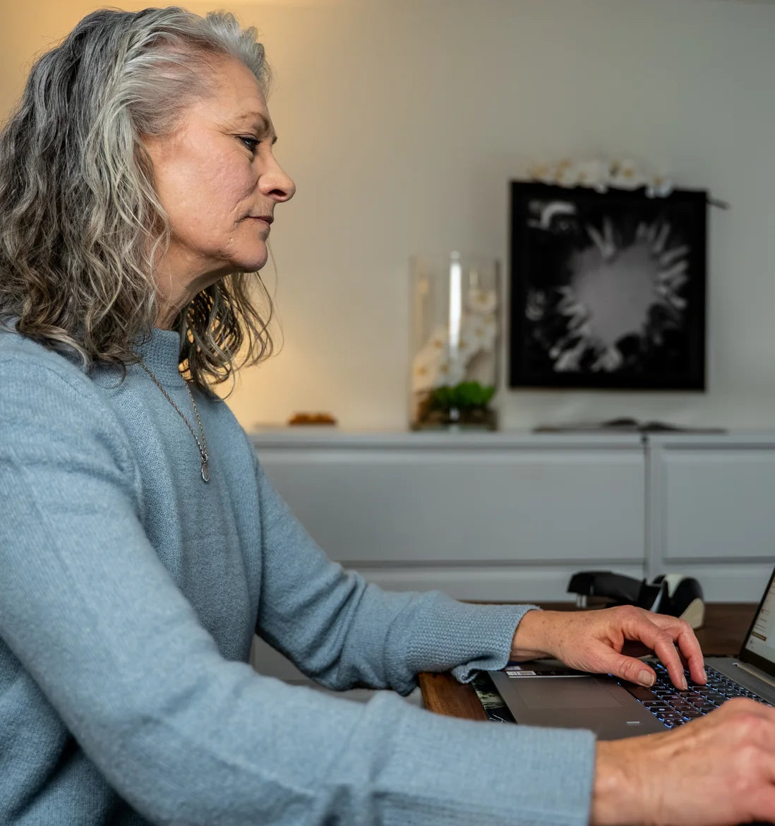 Woman with gray hair working on a laptop