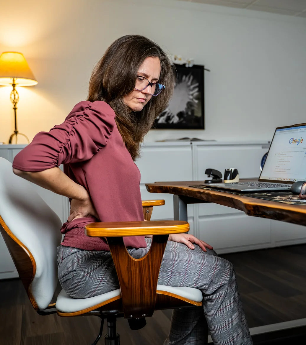 Woman holding her lower back at her desk